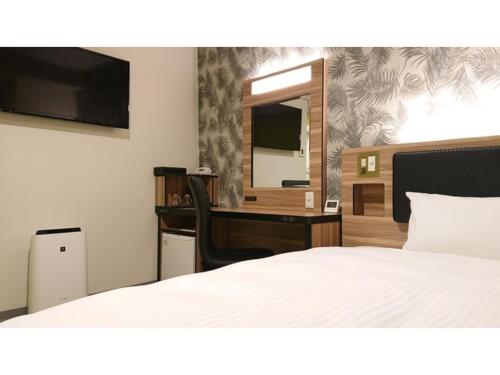 Schlafzimmer mit einem Bett, einem Schreibtisch und einem Spiegel in der Unterkunft Green Rich Hotel Okinawa Nago - Vacation STAY 55410v in Nago