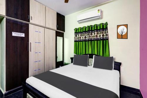 1 dormitorio con 1 cama y cortina verde en OYO SS Home Stay - An Unique Home Stay, en Tirupati
