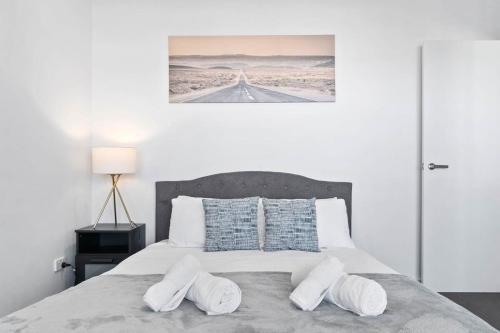 a white bedroom with a bed with two pillows at Lightview Oasis- Modern 2BR Apt- WiFi & Parking in Broadview