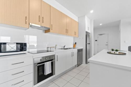 a white kitchen with white cabinets and appliances at Lightview Oasis- Modern 2BR Apt- WiFi & Parking in Broadview