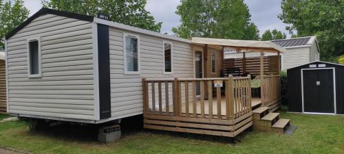 a tiny house with a porch and a deck at Mobil Home 3 chambres in Ouistreham