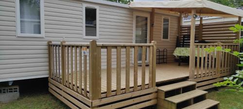 a wooden deck with an umbrella on a house at Mobil Home 3 chambres in Ouistreham