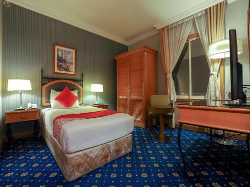 Habitación de hotel con cama y piano en City Plaza Hotel en Fujairah