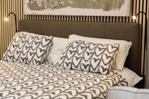 Una cama con almohadas blancas y negras. en Zen Orlando house en Taormina