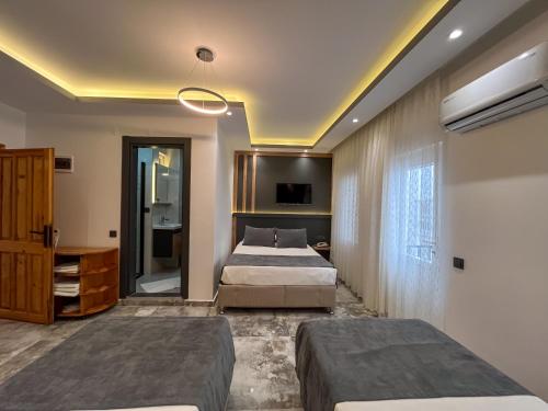 a hotel room with two beds and a television at Rain Hotel in Kizkalesi