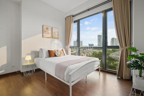 a white bedroom with a bed and a large window at Avalon by Kozystay - BSD in Tangerang