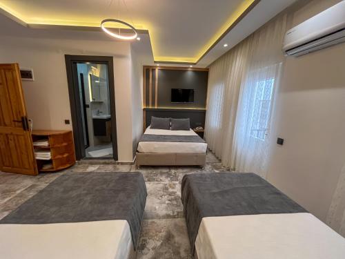 a bedroom with two beds and a television in it at Rain Hotel in Kizkalesi