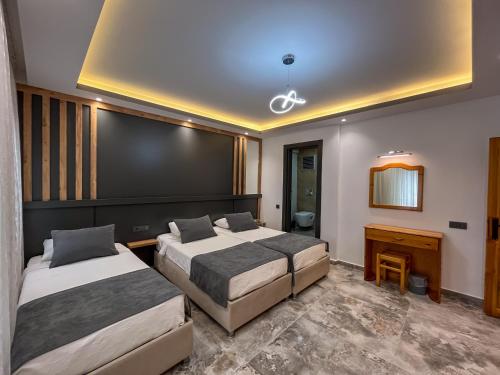 a hotel room with two beds and a desk at Rain Hotel in Kizkalesi