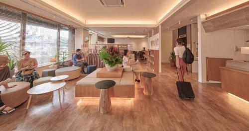 a lobby with people sitting in chairs and tables at Ishigakijima Hotel Cucule in Ishigaki Island