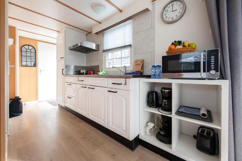 a kitchen with white cabinets and a clock on the wall at 85, Private, Parking - Nature - Central - AC - Serene! in Oisterwijk