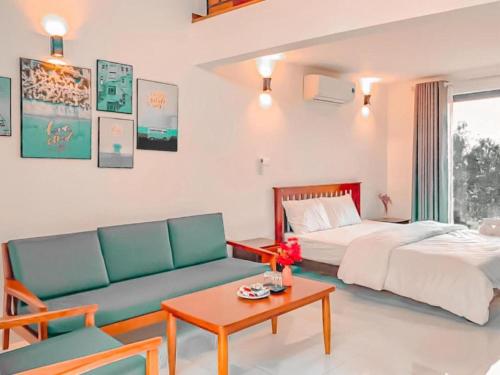 a bedroom with a bed and a couch and a table at Maryland Garden - Venustay in Ba Vì