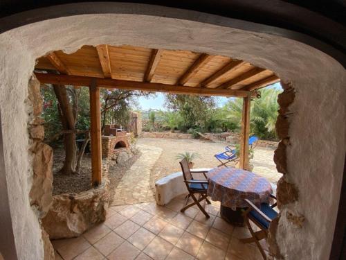 un patio con mesa, sillas y pared de piedra. en Mar D'Africa, en Lampedusa
