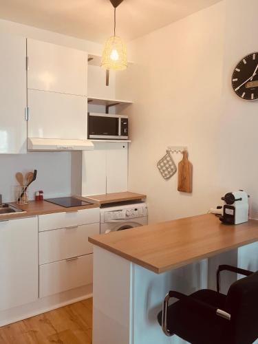 une cuisine avec des placards blancs et une horloge murale dans l'établissement chez Jin Jin, à La Rochelle