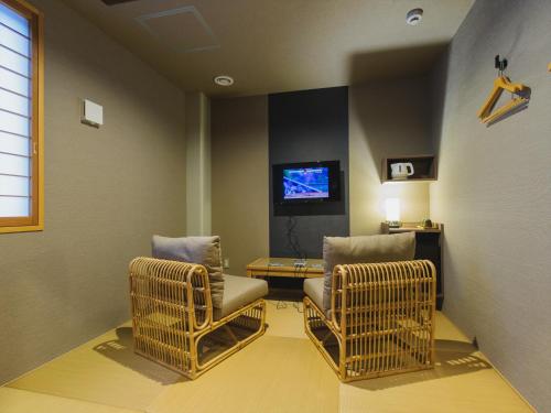 two chairs and a table in a room with a tv at Giappo Franca Kyoto in Kyoto
