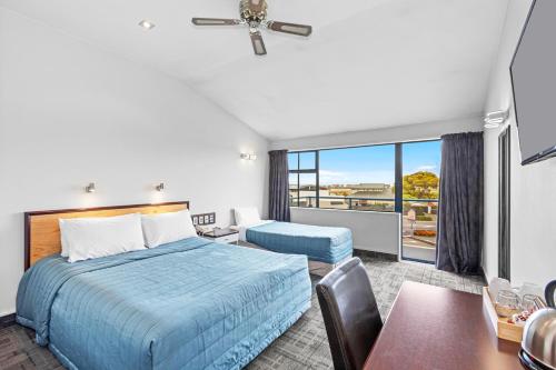 a bedroom with a bed and a desk and a window at Comfort Hotel Benvenue in Timaru