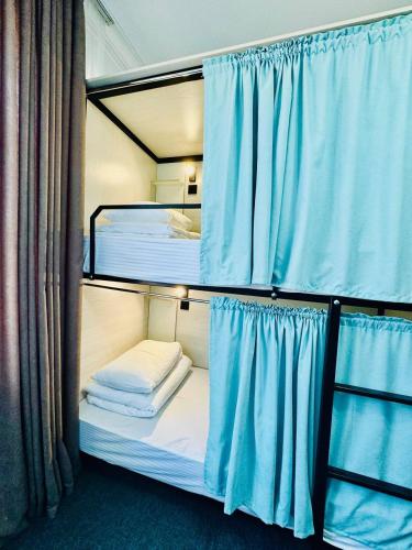 a room with two bunk beds with blue curtains at Asia Hostel in Shymkent