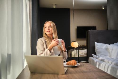 a woman sitting at a table with a cup of coffee at Boutique Residence Gdańsk in Gdańsk