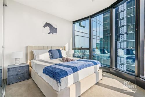 een slaapkamer met een bed en een groot raam bij Sleep in the Clouds Level 30 Aus 108 - sleeps 6 in Melbourne