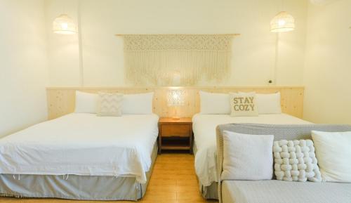 a room with two beds and a chair in it at Cozy Blue B&B in Taitung City