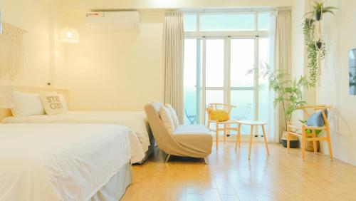 a white bedroom with a bed and a chair at Cozy Blue B&B in Taitung City