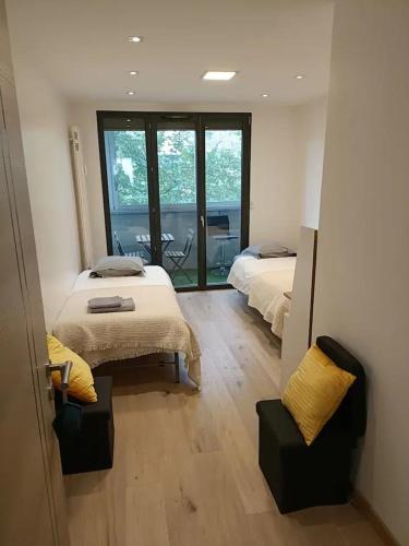 a bedroom with two beds and a view of a balcony at Chambre privée 1 chez Vincent - Appartement partagé Gare - Centre ville -WIFI in Annecy