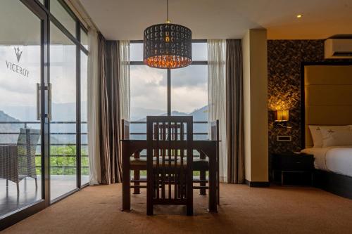 a bedroom with a table and a chair in front of a window at Viceroy Luxury Mountain Resort and Spa in Munnar