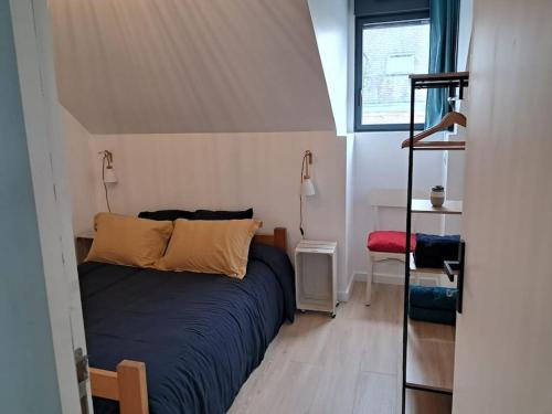 une chambre avec un lit avec des draps bleus et une fenêtre dans l'établissement Appartement T2 proche centre/gare, à Lorient