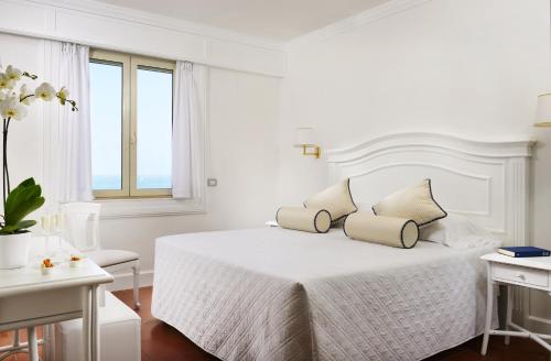 a white bedroom with a white bed with two pillows at Hotel President in Viareggio