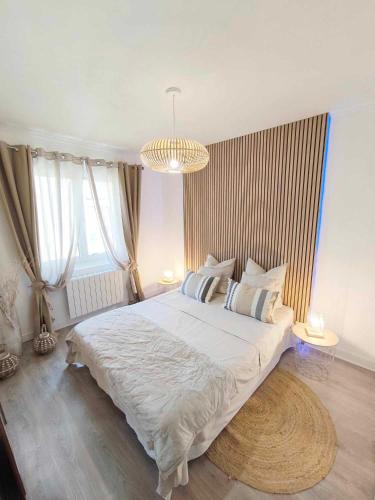ein Schlafzimmer mit einem großen weißen Bett und einem Kronleuchter in der Unterkunft La suite Carolo in Charleville-Mézières
