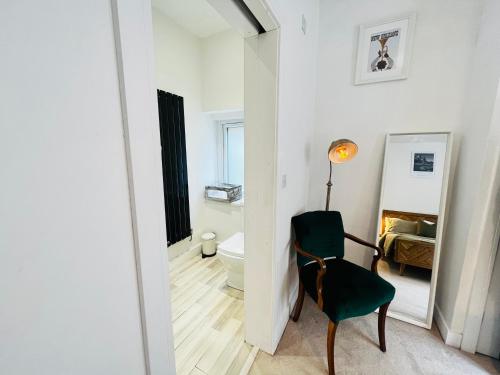Habitación con silla verde y baño. en Leah Suite by Koya Homes en Barry