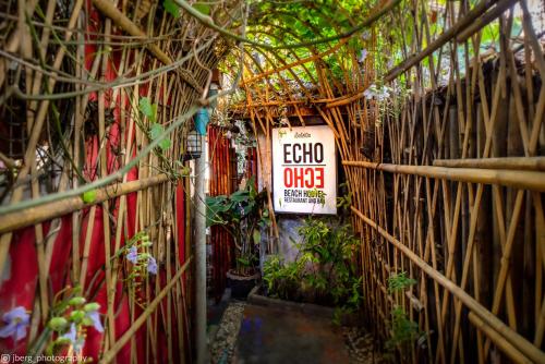 a fence with a sign on it with plants at Echo Beach Hostel in Baan Tai