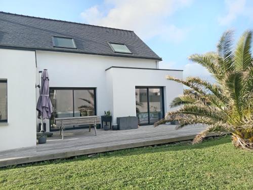 une maison blanche avec un banc et un palmier dans l'établissement Casa Breizh & Fun, à Erdeven