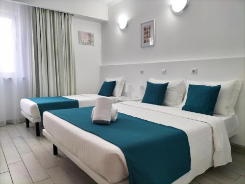 2 Betten in einem blau-weißen Zimmer in der Unterkunft Residencial Tropicália AL in Praia da Barra