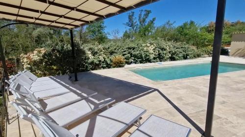 un patio avec une table et des chaises et une piscine dans l'établissement Bastide La Maura dans le massif des Maures, à Vidauban