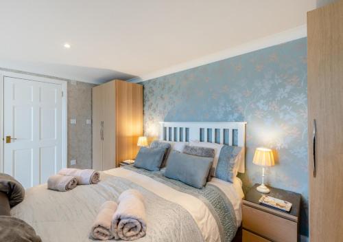 - une chambre avec un grand lit aux murs bleus dans l'établissement Highridge Apartment, à Wooler
