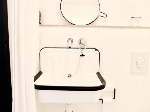 un lavabo blanc dans une salle de bain avec un miroir dans l'établissement L'aixois - Terrasse au cœur d'Aix-en-Provence #1, à Aix-en-Provence