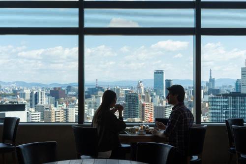 a man and woman sitting at a table in front of a window at Nagoya JR Gate Tower Hotel in Nagoya