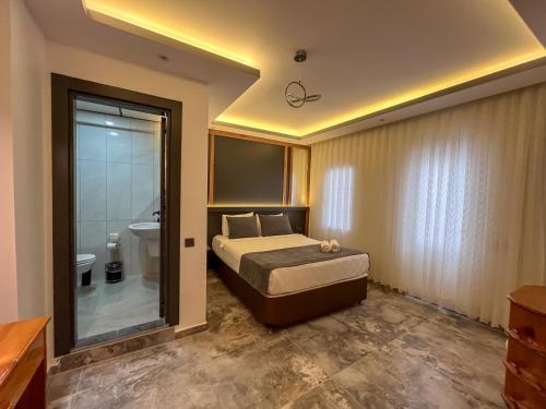 a bedroom with a bed and a bathroom with a toilet at Rain Hotel in Kizkalesi