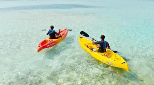 two people in kayaks in the water in the ocean at Madi Grand Maldives in Fulidhoo