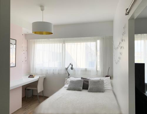 une chambre blanche avec un lit et un bureau dans l'établissement Plage et hippodrome. Parking, à Cagnes-sur-Mer