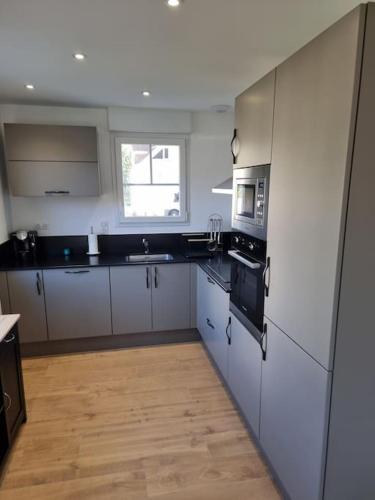 a kitchen with white appliances and a wooden floor at Maison familiale avec jardin in Neufchâtel-Hardelot