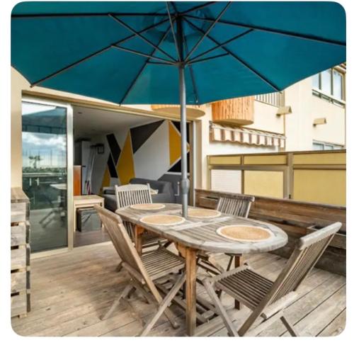 une table en bois avec des chaises et un parasol sur une terrasse dans l'établissement Petite endroit splendide., à Six-Fours-les-Plages