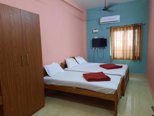 a bedroom with two beds and a cabinet and a television at hotel sudhara in Tirukkadaiyūr