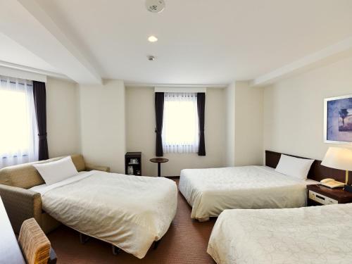 a hotel room with two beds and a couch at Hotel Courtland in Nagano