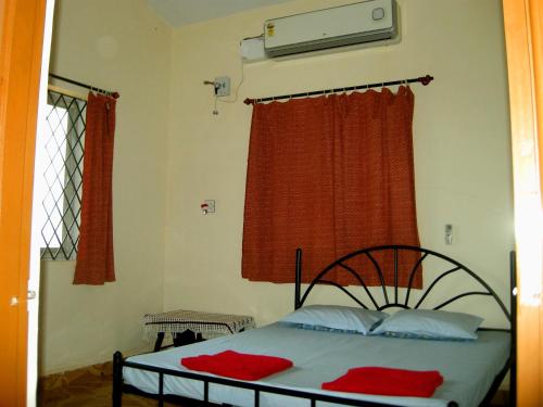 a bedroom with a bed and a window with red curtains at Joe And Marietta's Guesthouse in Calangute