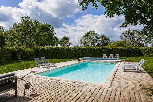 une piscine avec des chaises et une terrasse en bois dans l'établissement Logis La Tour - Gîte La Tour, à Saint-Laurent-de-la-Salle