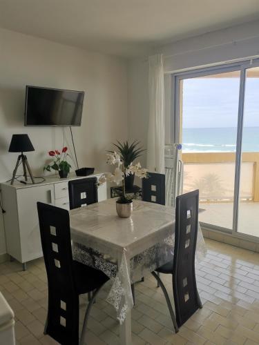 une salle à manger avec une table et des chaises avec vue sur l'océan dans l'établissement Les sablines, à Canet