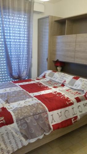 - un lit avec une couverture rouge et blanche dans l'établissement Les sablines, à Canet