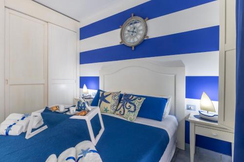 a blue and white bedroom with a clock on the wall at Home Borgo Rio Favara in Ispica