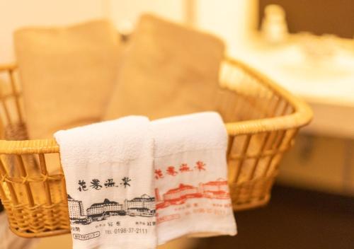 twee handdoeken in een rieten mand op een tafel bij Hotel Hanamaki in Hanamaki
